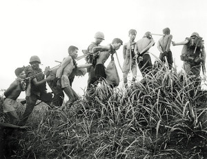 06 Nov 1965, Da Nang, South Vietnam --- 11/6/1965- Da Nang, South Vietnam- Viet Cong prisoners with their hands tied behind their backs are marched along in a small group where each man is joined to the other by cloth bands around the neck. A marine leads the Viet Cong on a halter during a marine operation from Da Nang. --- Image by © Bettmann/CORBIS
